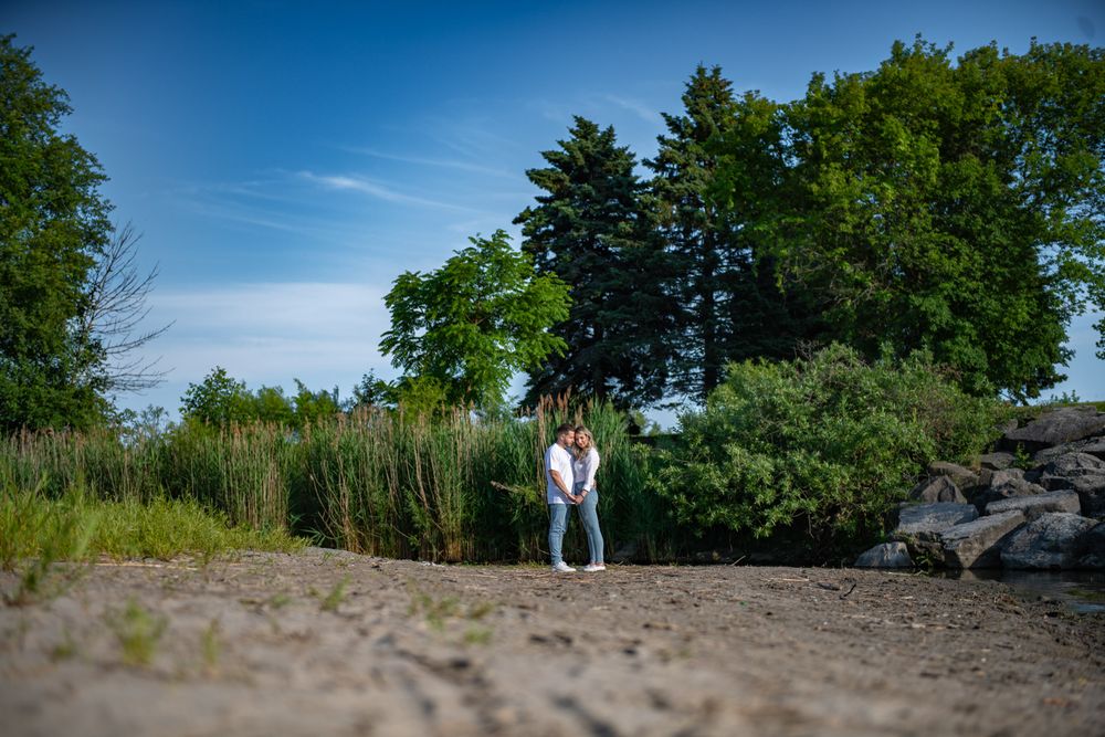 Couple sharing an intimate moment on a sandy path with lush greenery in background.