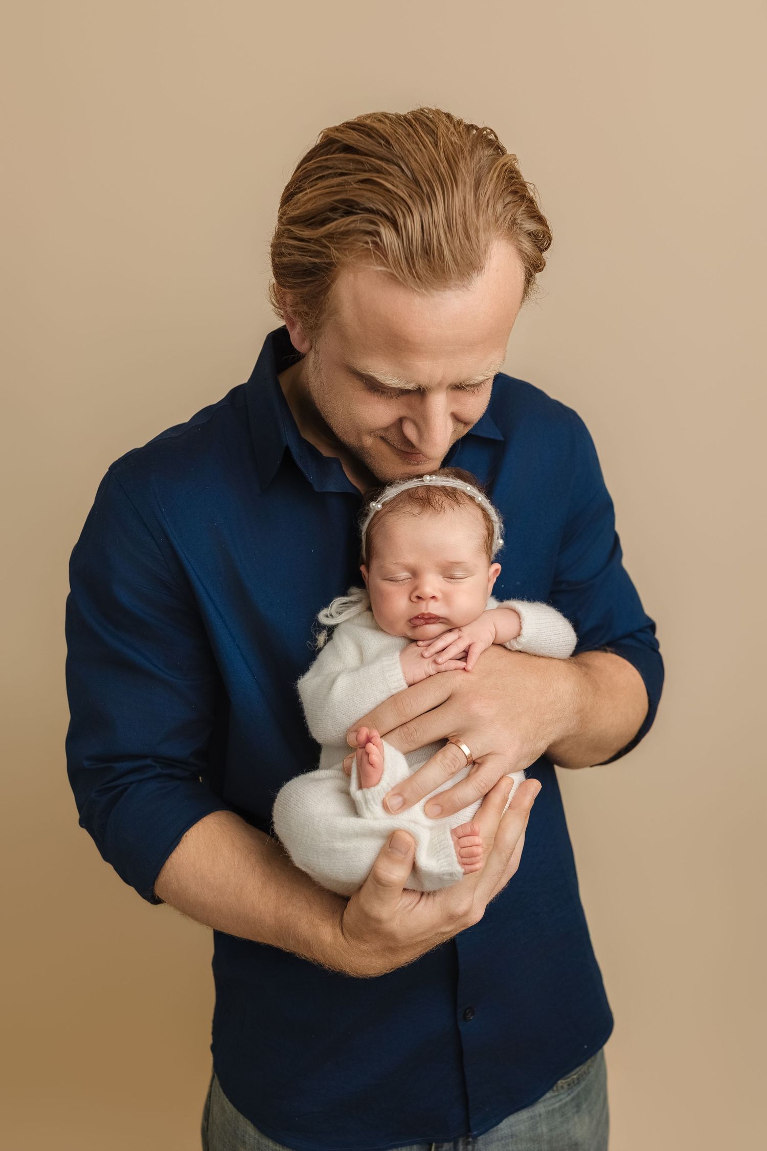 Dad lovingly holds his newborn daughter, dressed in cozy white knits. Captured by Charlottesville baby and family photographer.