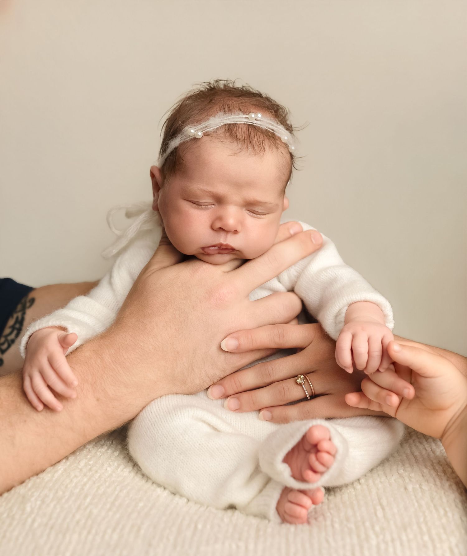 A family's hands cradle their newborn sister in white, captured by Charlottesville baby and family photographer, Somerset Portraits.