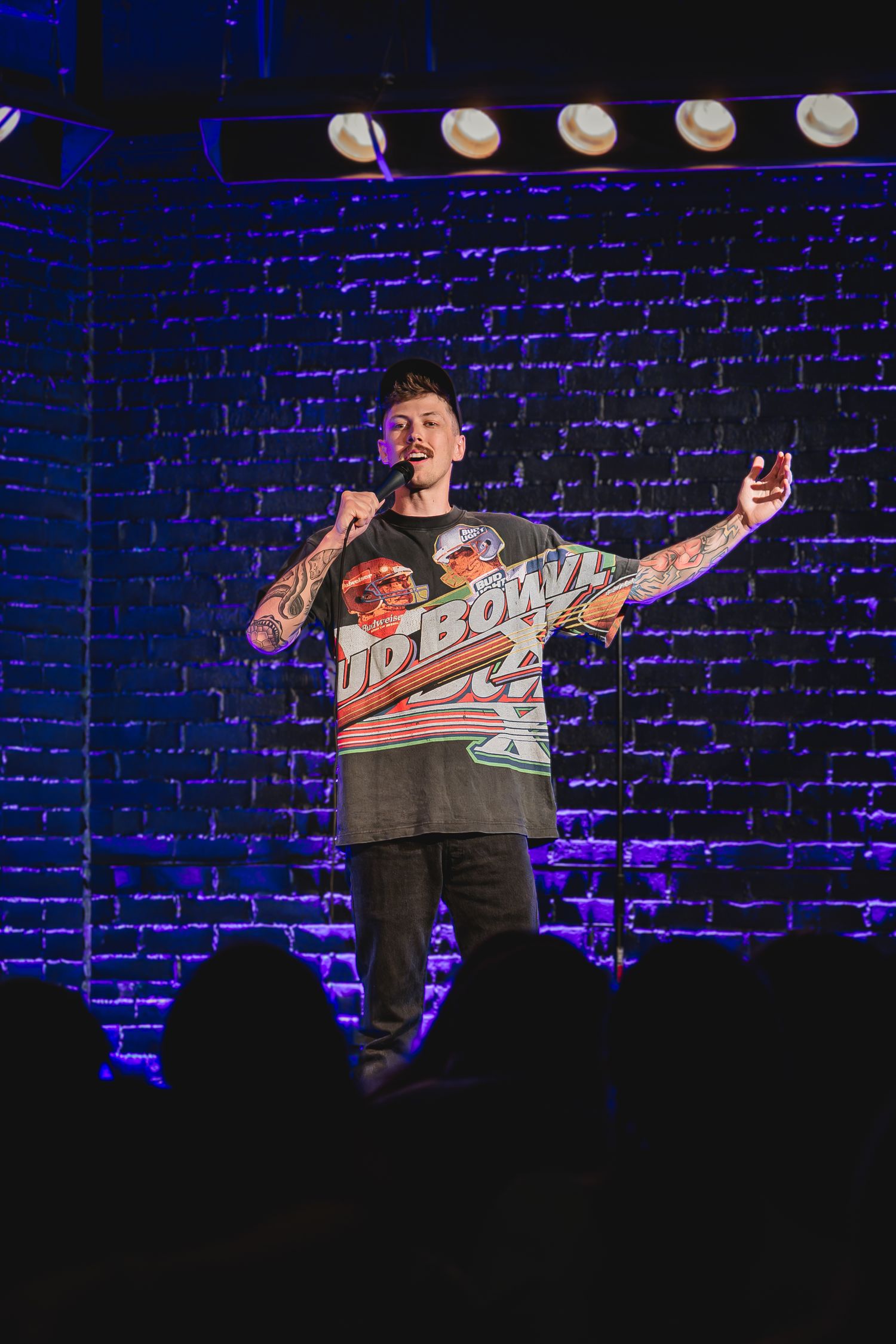 Cam Bertrand the comedian performing stand-up comedy on stage holding a microphone at Side Splitters Comedy Club Tampa. Videography. Photo