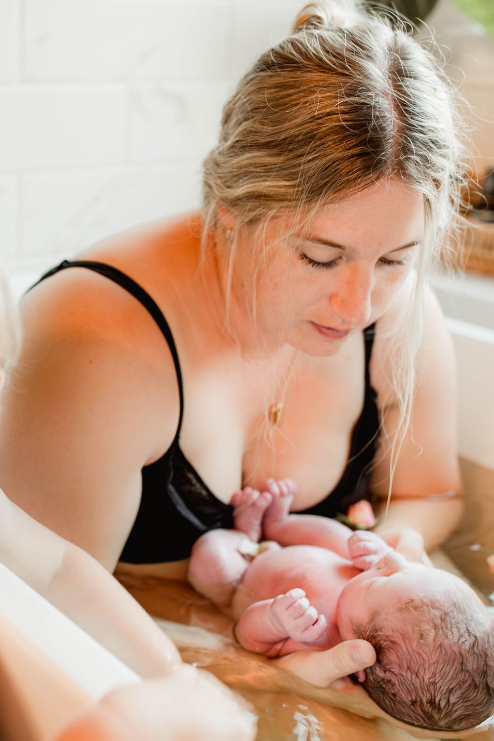 Mother holding her newborn baby moments after a water birth in a birthing pool.