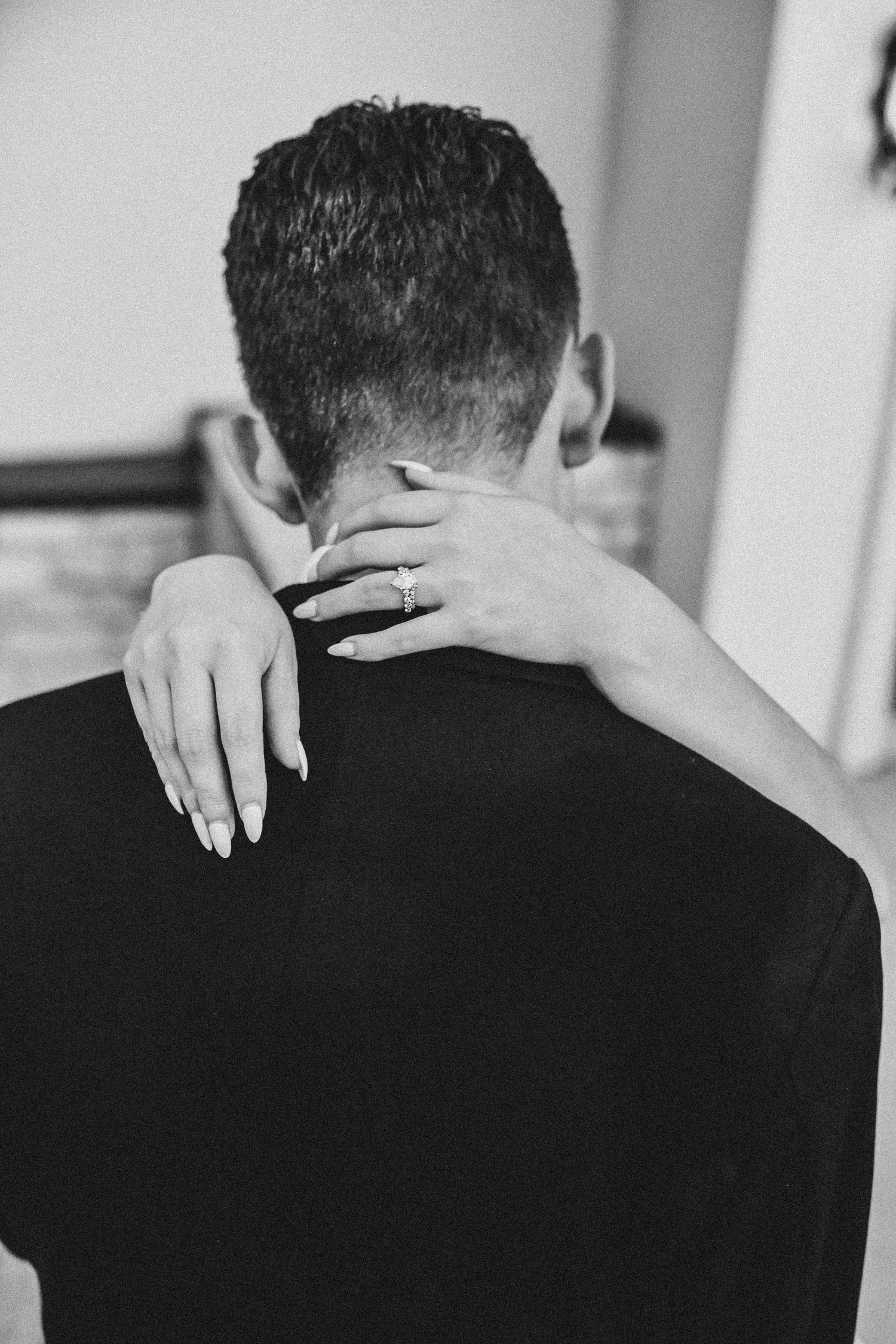 a bride holds her groom and her wedding ring shines into the camera
