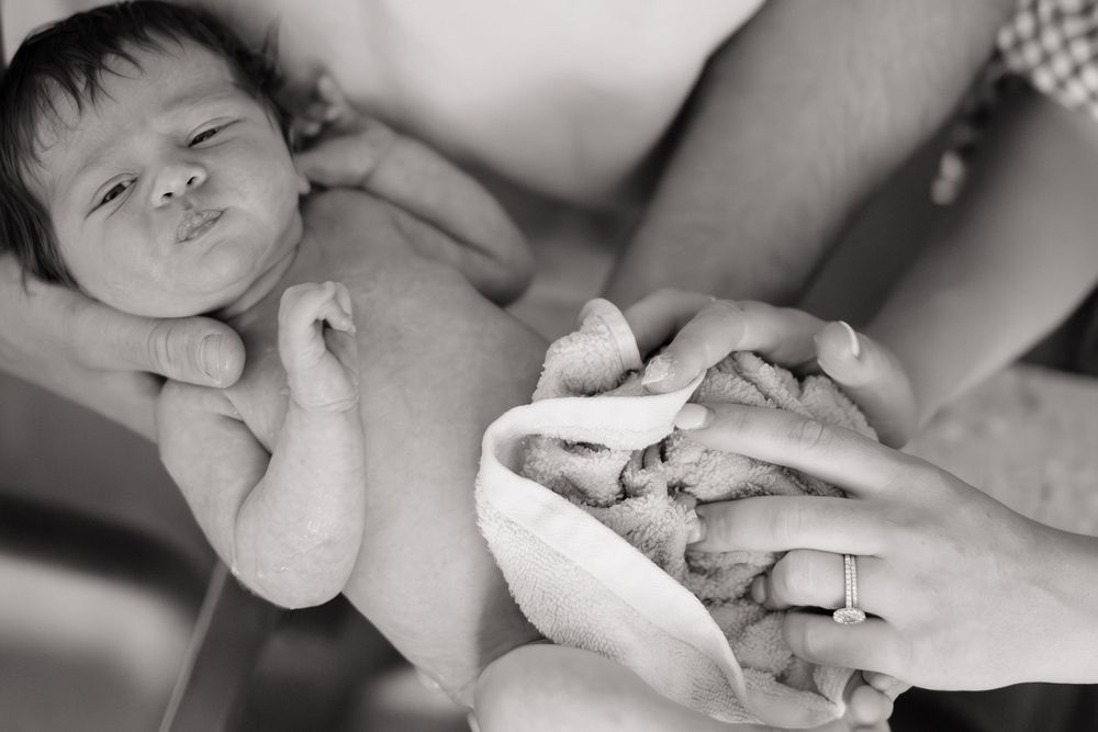 newborn baby being wrapped in towel after bath