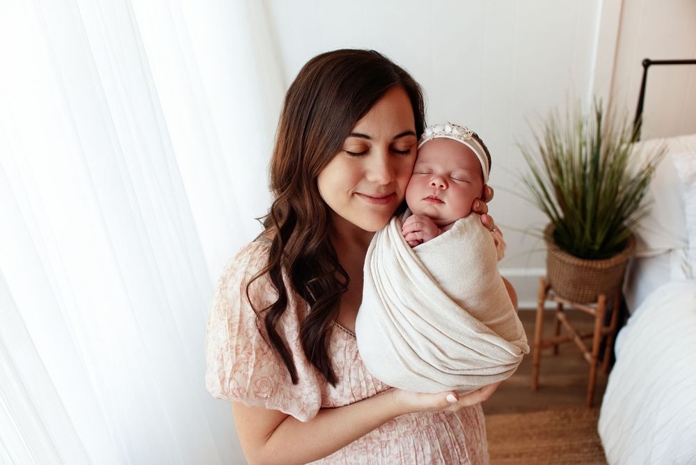 Tender family lifestyle photos with soft white bedding and indoor plant decor.