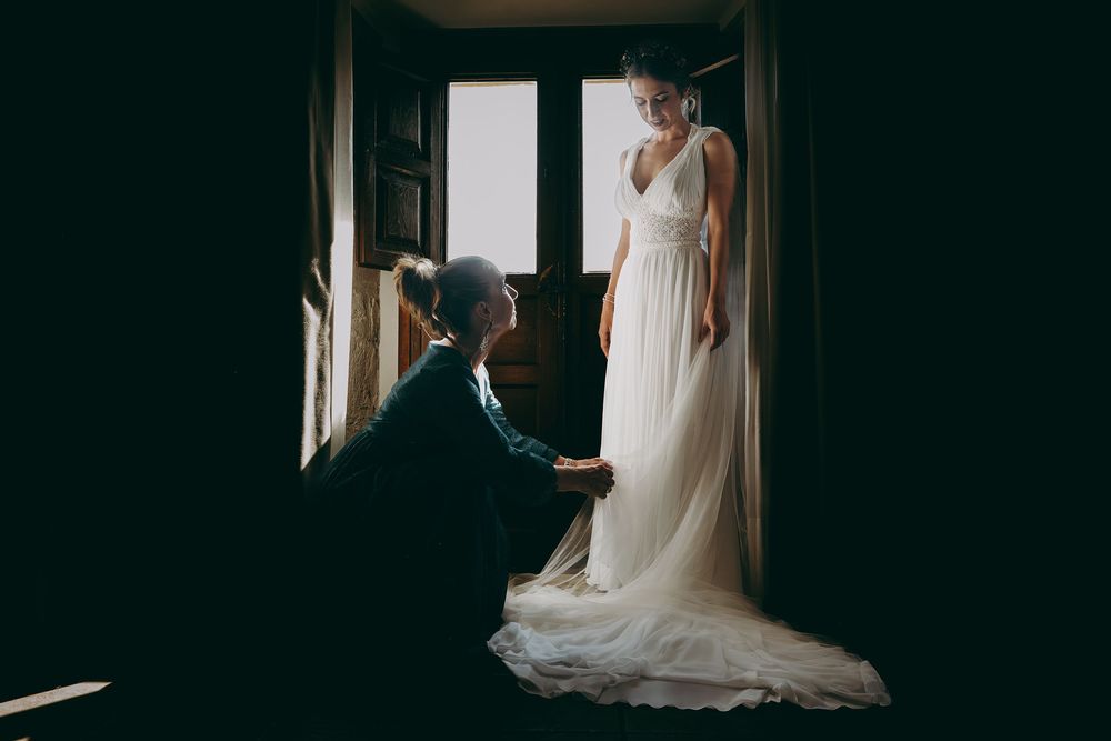 Madre ayudando a su hija a colocarse el vestido durante los preparativos de una boda en Asturias.