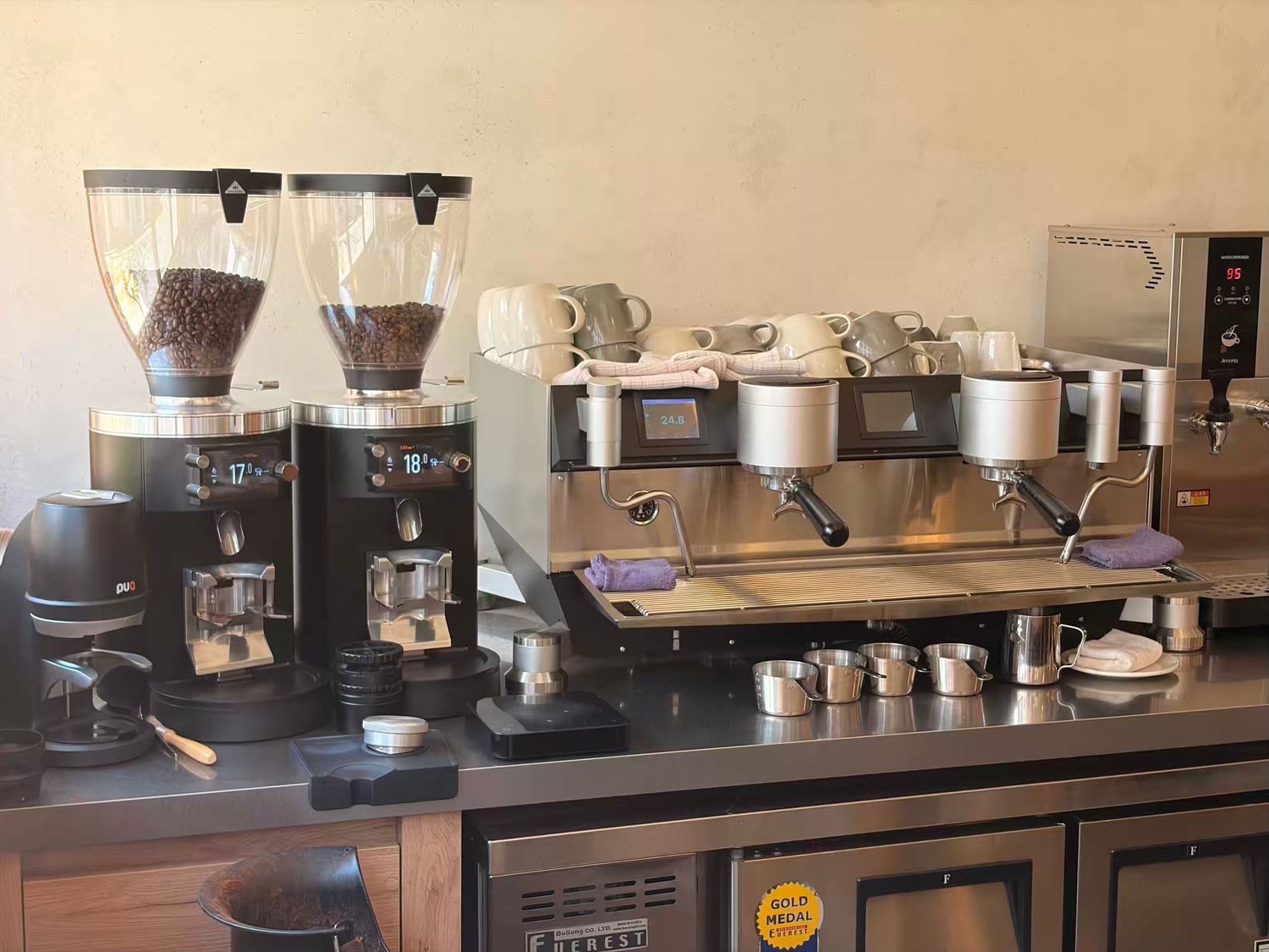 Professional espresso machine with dual coffee grinders on a commercial bar counter in a modern cafe setting.