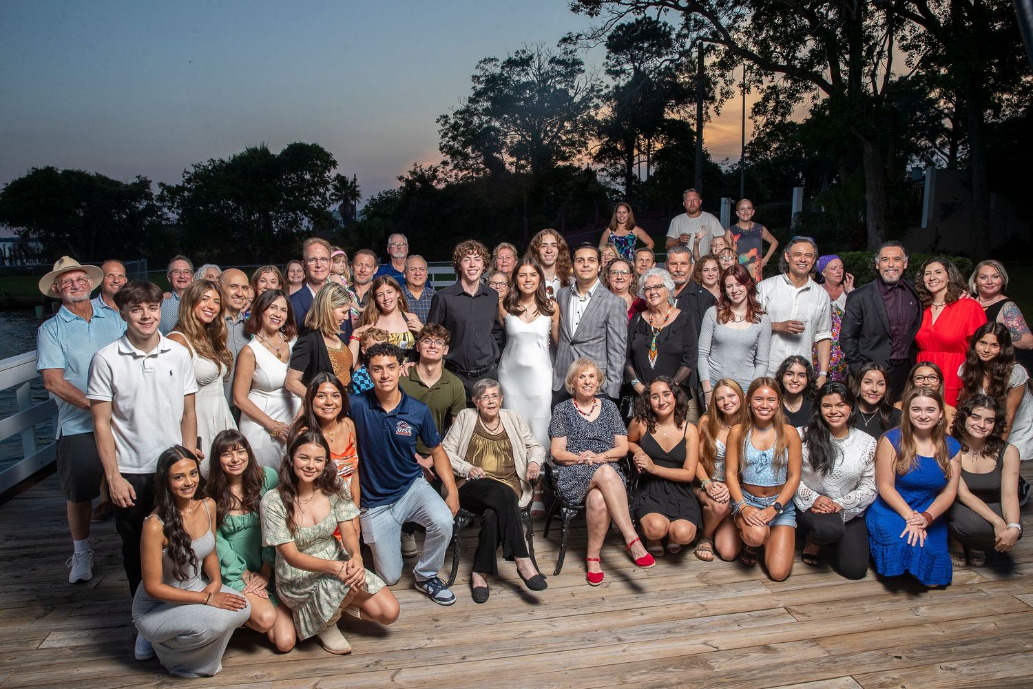 Large group photo of formally dressed people outdoors at dusk.