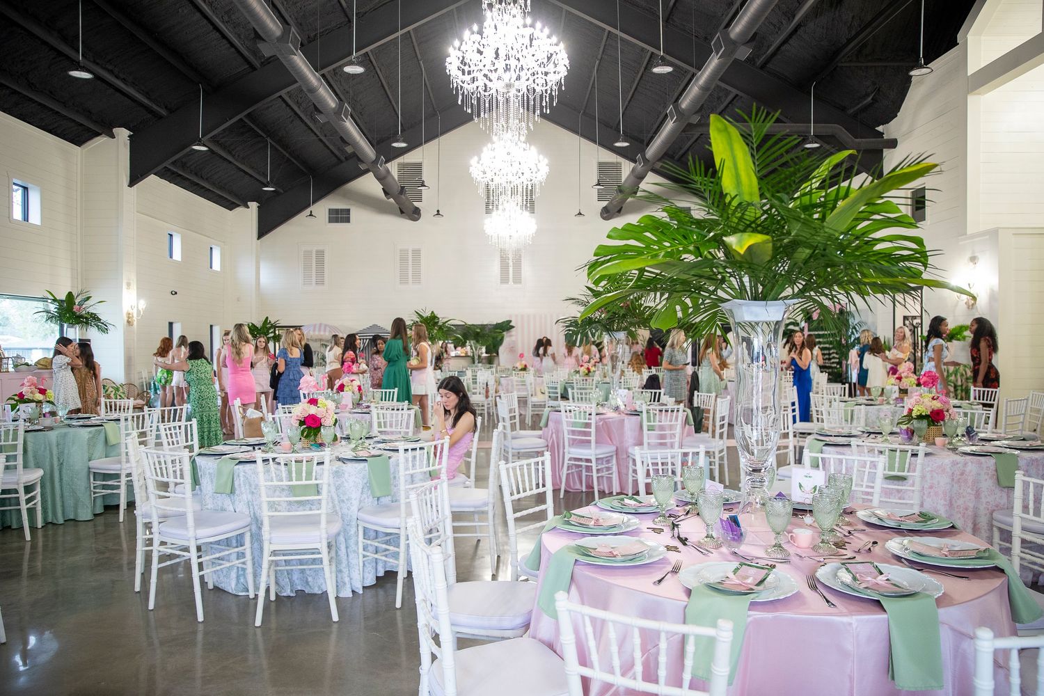 Modern event space with white chiavari chairs and crystal chandeliers.