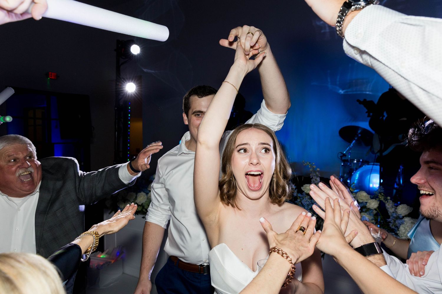 Bride and groom share a romantic dip kiss on dance floor surrounded by guests holding sparklers at night wedding reception.