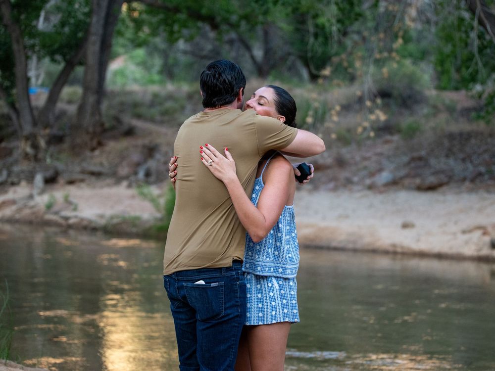 Romantic couple sharing a tender kiss while standing in a shallow creek in nature.