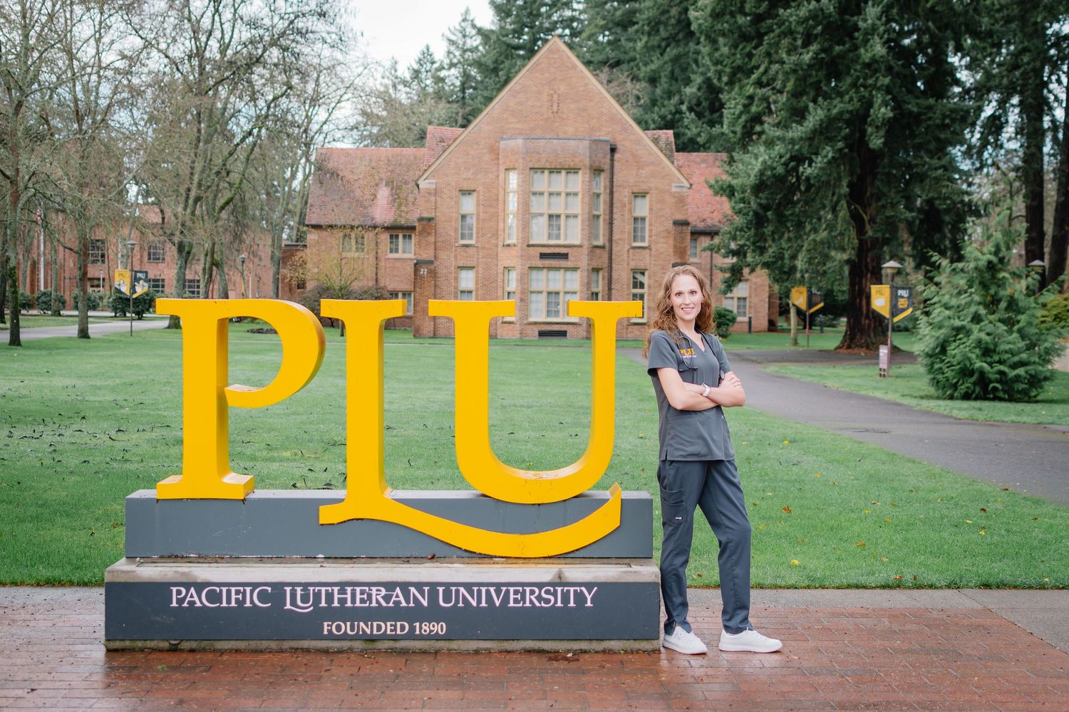 Pacific Lutheran University nursing graduate posing beside campus sign during Tacoma graduation session