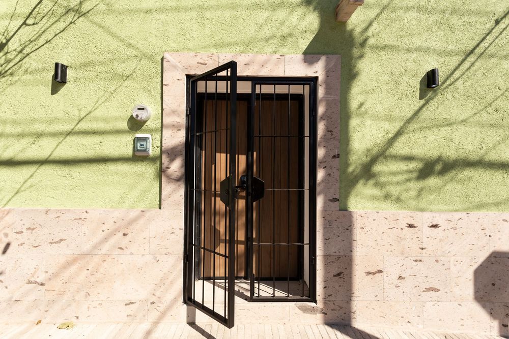 Outdoor patio area with green walls and terracotta tiled flooring showing iron security gates.