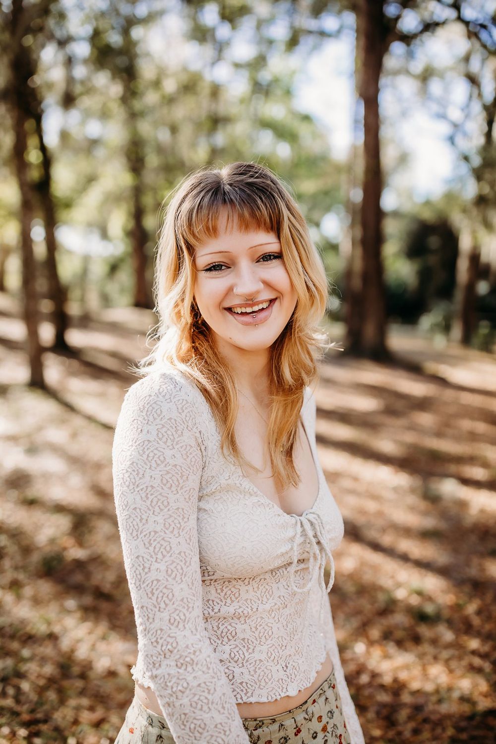 Three outdoor portrait photos in a wooded setting with dappled sunlight and fall leaves on the ground.