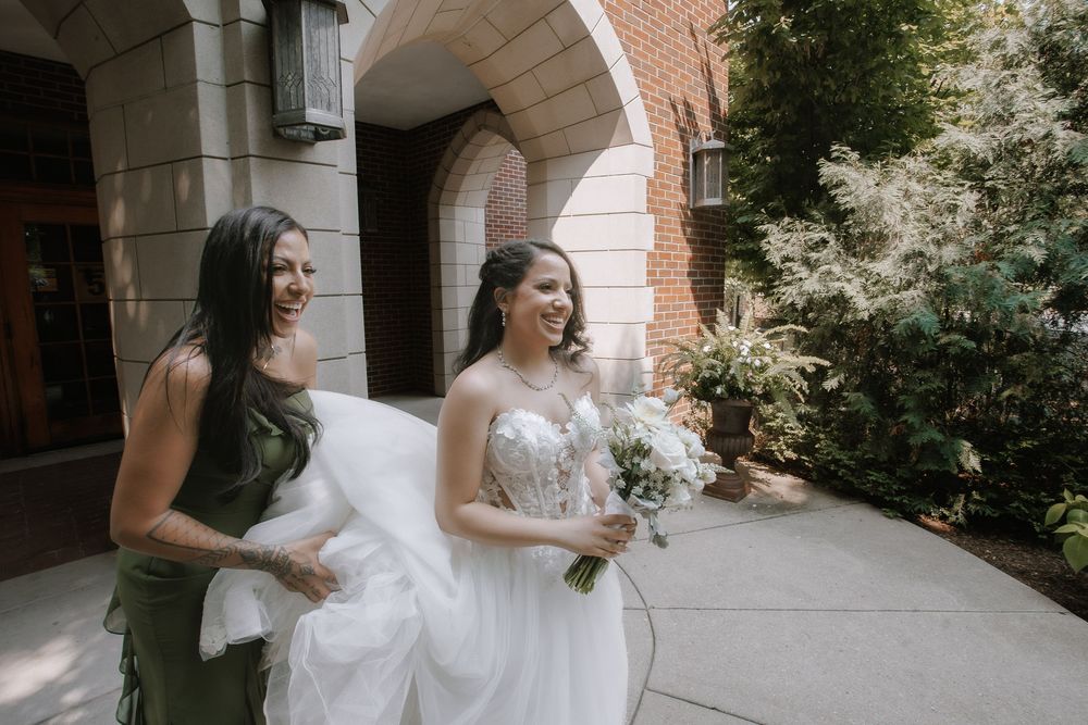 Two people share a joyful moment together in formal attire outside an arched brick building entrance.