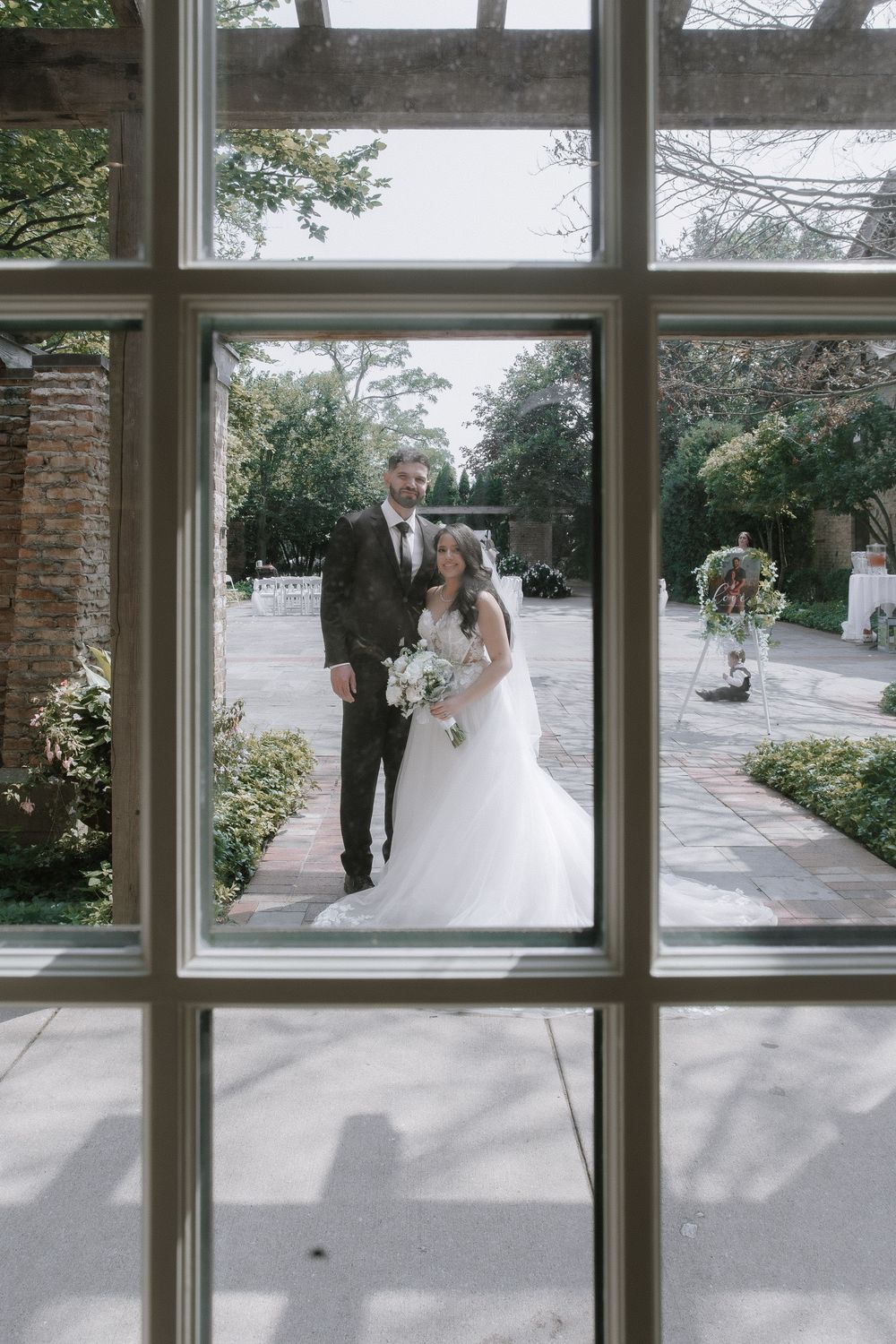 A series of wedding photos seen through windows showing a bride and groom walking along a garden path.