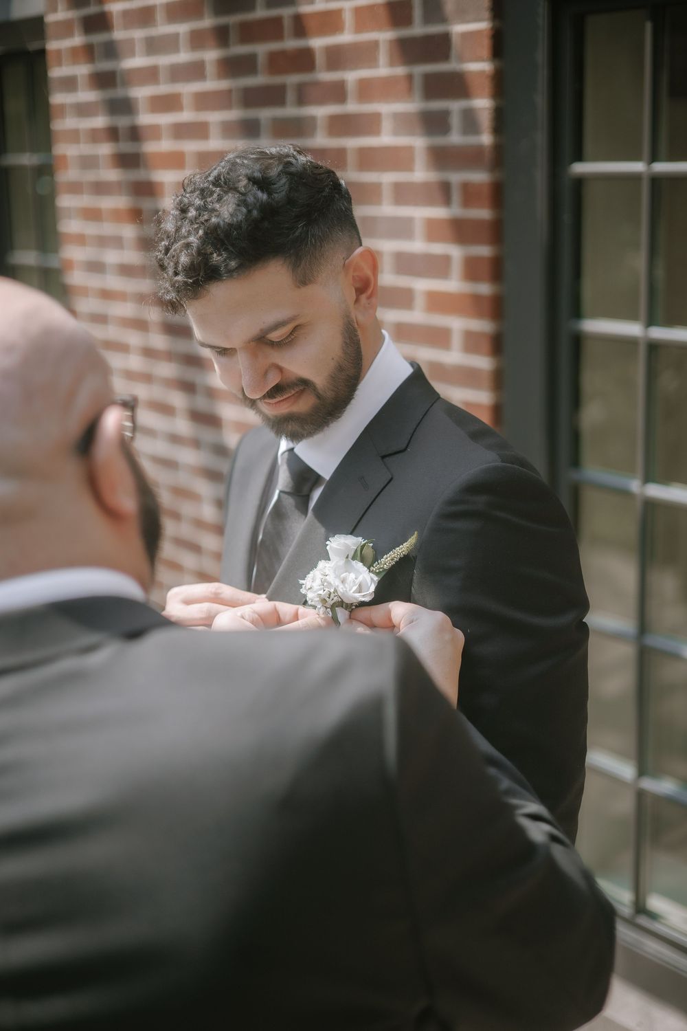A close-up view of groomsmen adjusting boutonnieres on their dark suits before the ceremony.