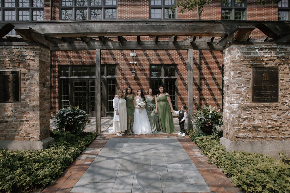Wedding party members posed outside a historic brick building with stone architecture details.