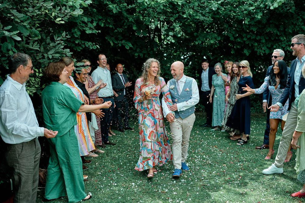 Party guests in colorful summer attire gather outdoors on a lush green lawn for a casual social event.