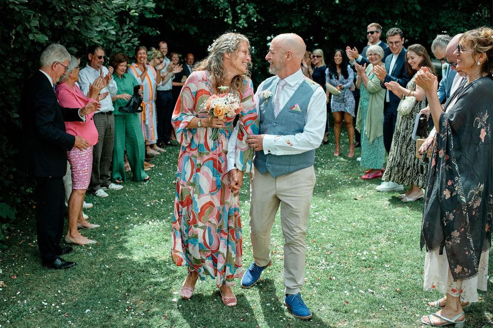Wedding guests gather on a lush green lawn during an outdoor summer celebration while watching musical performers.
