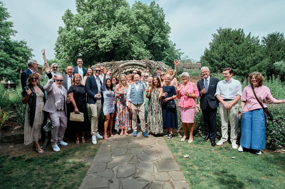 Wedding guests gather on a grassy lawn during an outdoor reception celebration.