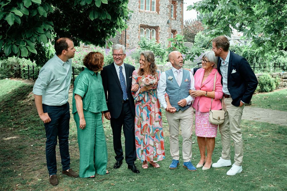 A group of people gathered outdoors for a casual social event in a garden setting wearing summer attire.