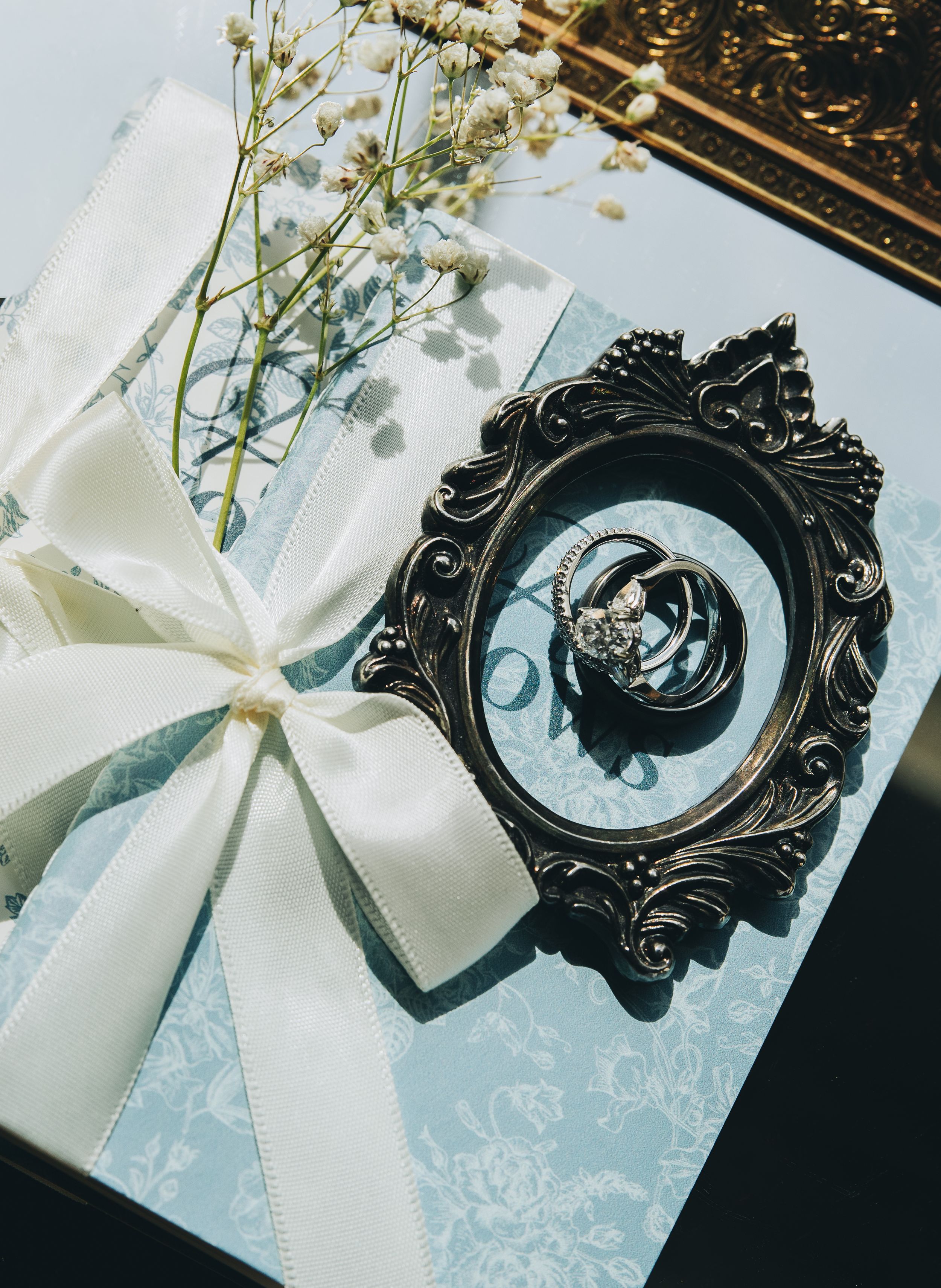 Series of elegant wedding invitations with ornate black frames and white bows on light blue damask paper backgrounds.