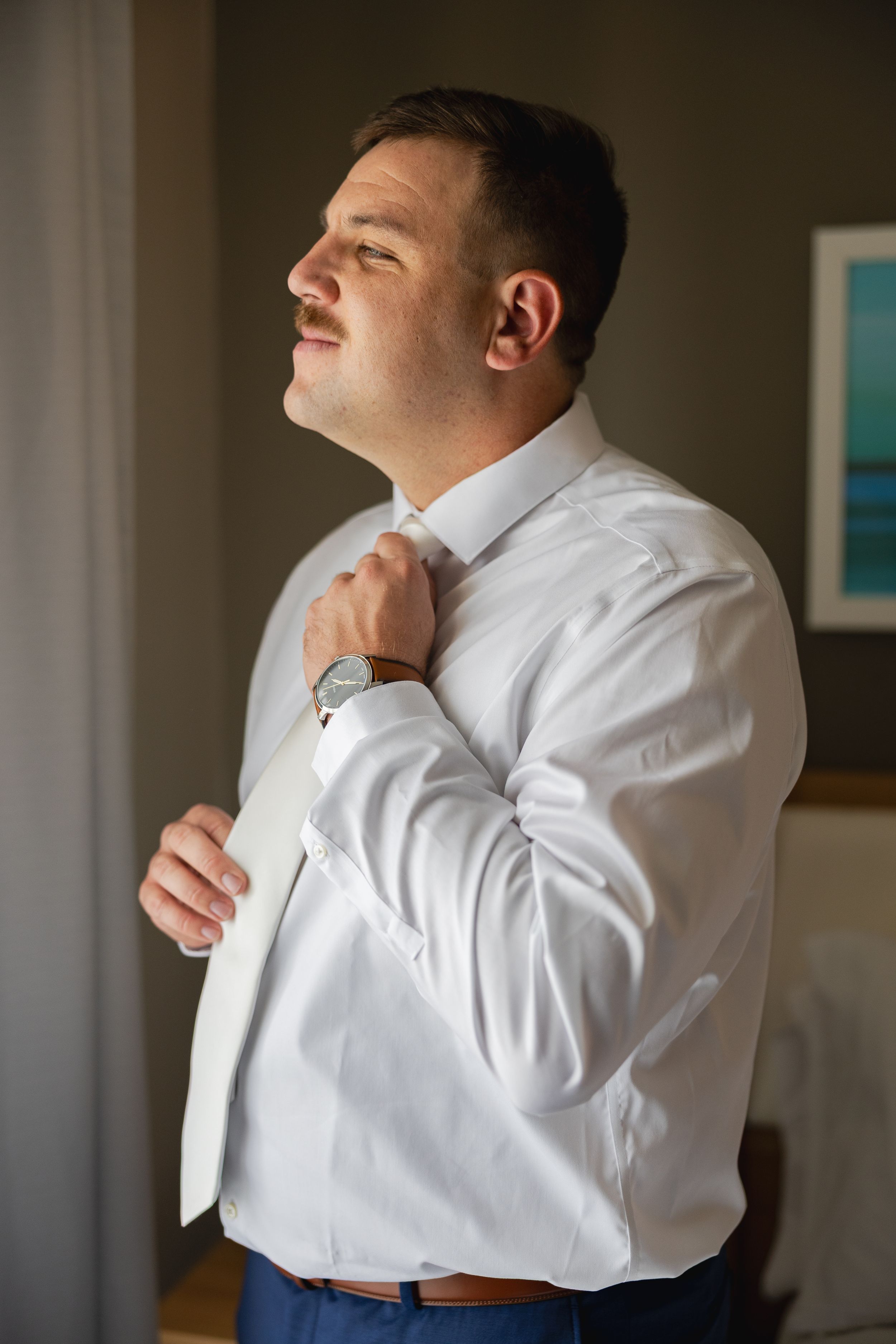 Series of photos showing someone adjusting a white dress shirt collar and tie in an indoor setting.