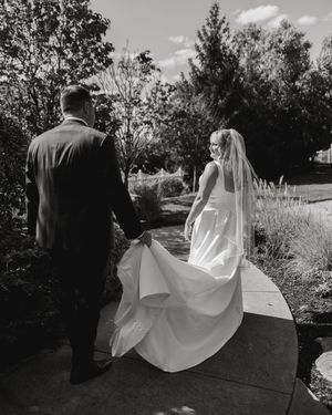 Black and white photos capture a flowing wedding dress train moving along an outdoor path.
