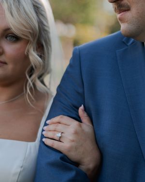 Close-up details of a romantic first look moment between newlyweds in navy and white attire.