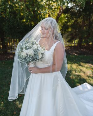 Beautiful bridal photos featuring a long white dress and delicate bouquet in natural lighting.