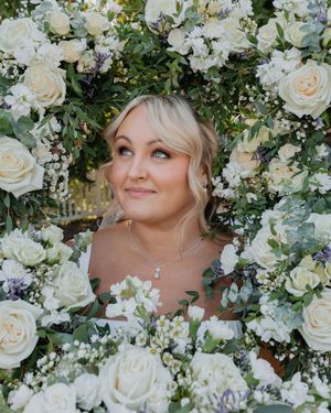 White and cream roses surround and frame a wedding moment in an elegant floral display.