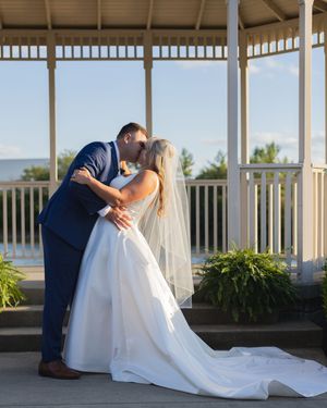 Wedding couple sharing intimate moments under a covered patio with flowing white dress and veil.