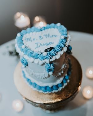 Four photos showing a round buttercream cake with blue and white frosting decorations on a metallic cake stand.