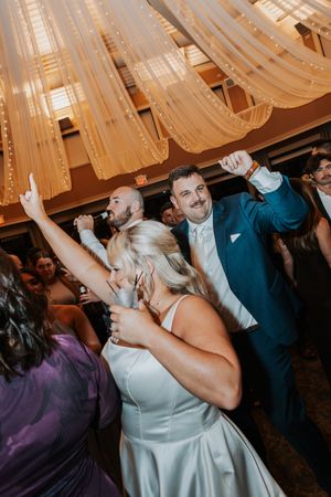 Wedding reception dance party with guests celebrating under draped fabric ceiling decorations.