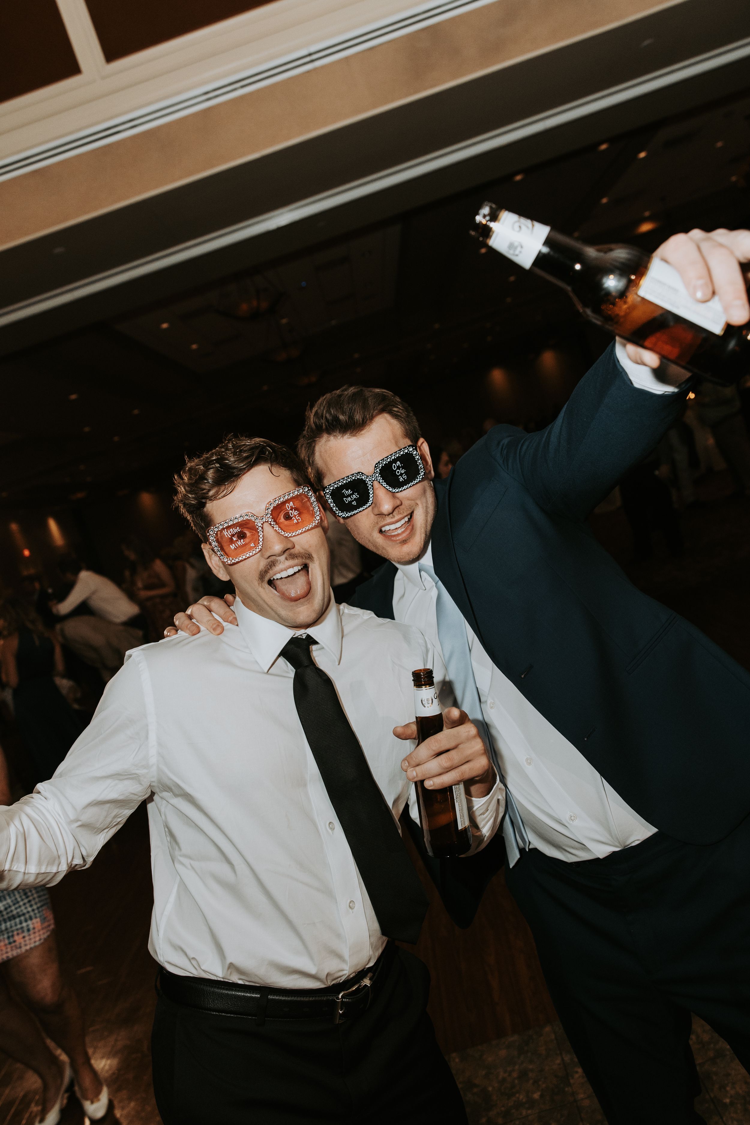 Two people in formal attire dancing and laughing together at a dimly lit celebration or party.