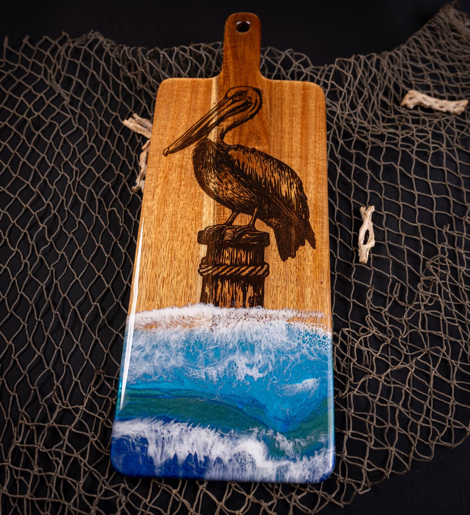 Ocean wave resin art on wood with fishnet backdrop showcases a crashing blue wave against natural timber grain.