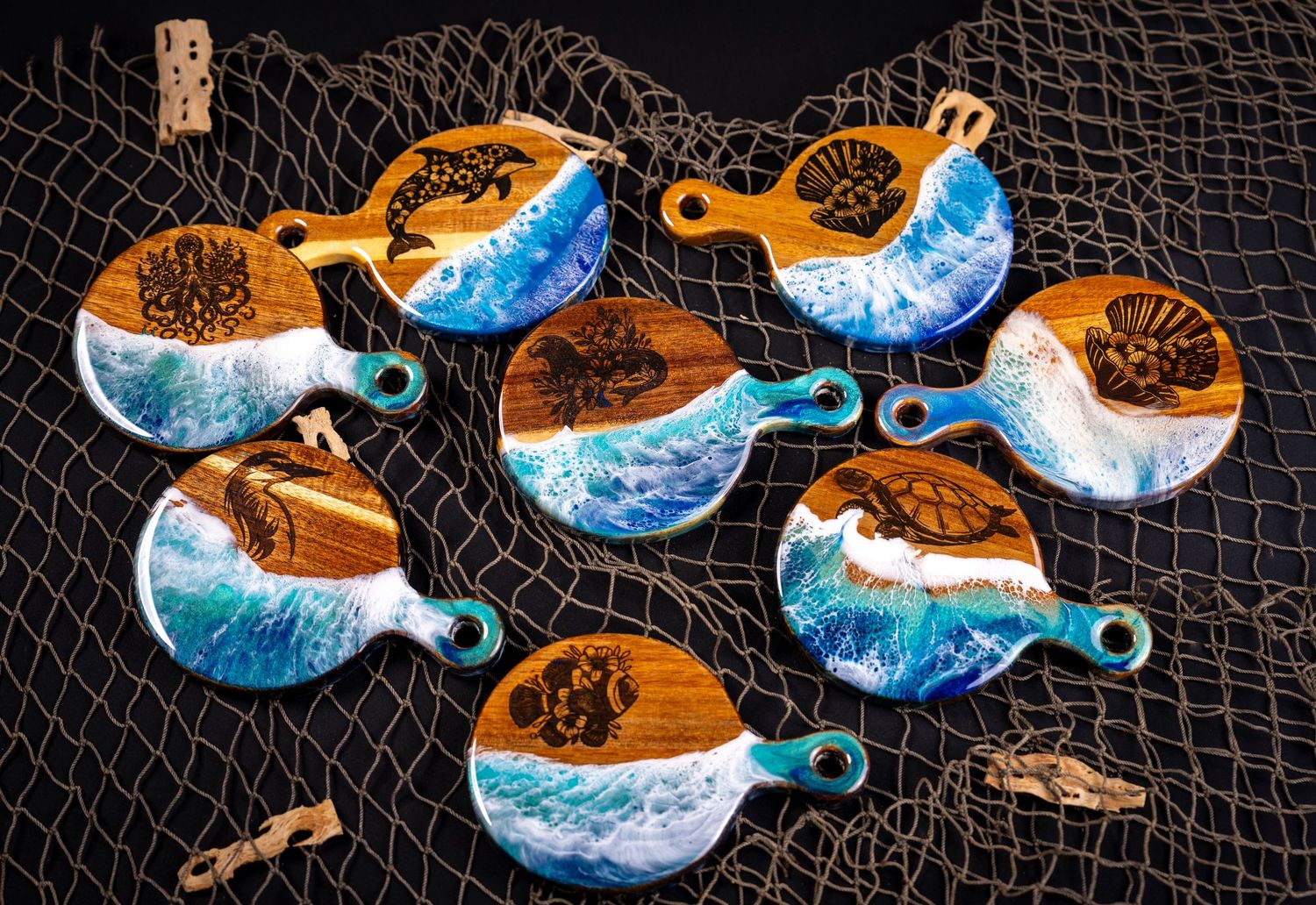 Collection of small round wooden coasters featuring blue ocean wave resin art displayed on dark fishing net background.
