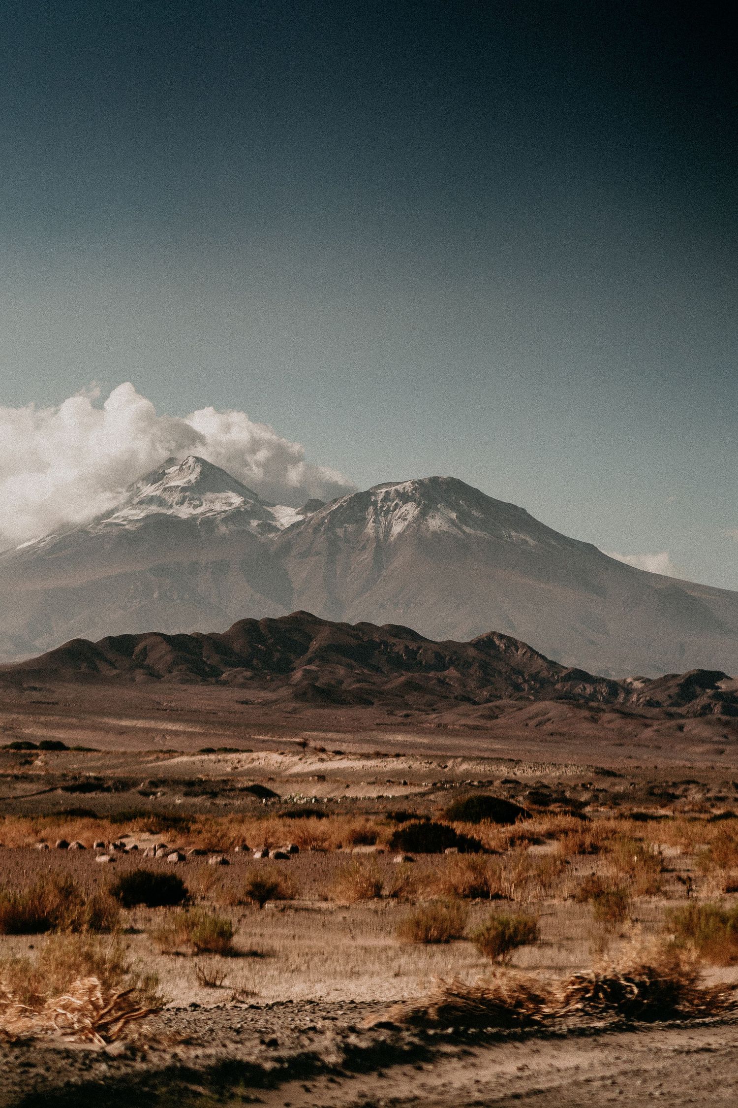 Dramatic mountain landscape with clouds rolling over peaks in desert terrain.