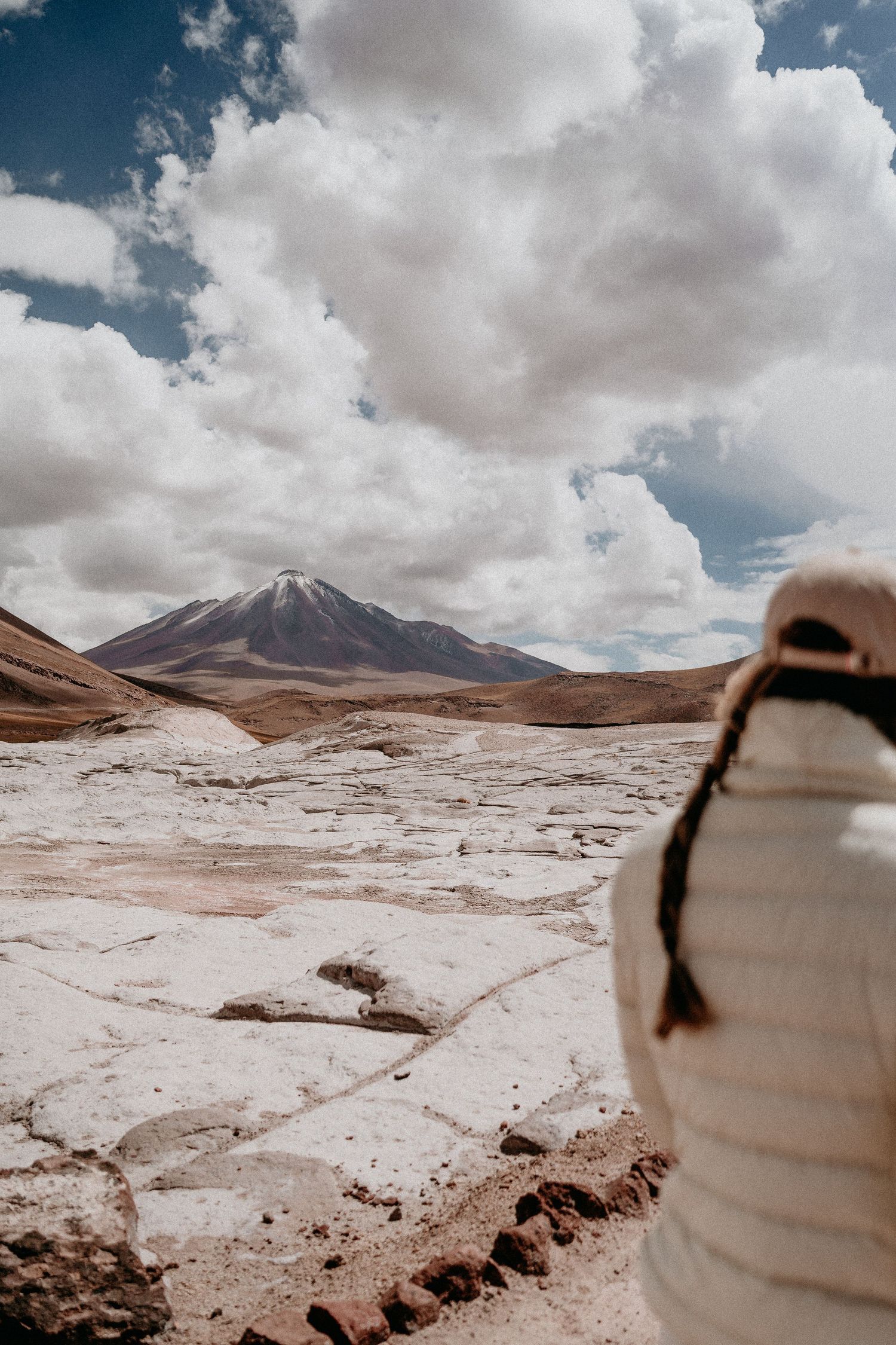 Desert landscape with snowy mountain peaks and dramatic cloud formations.