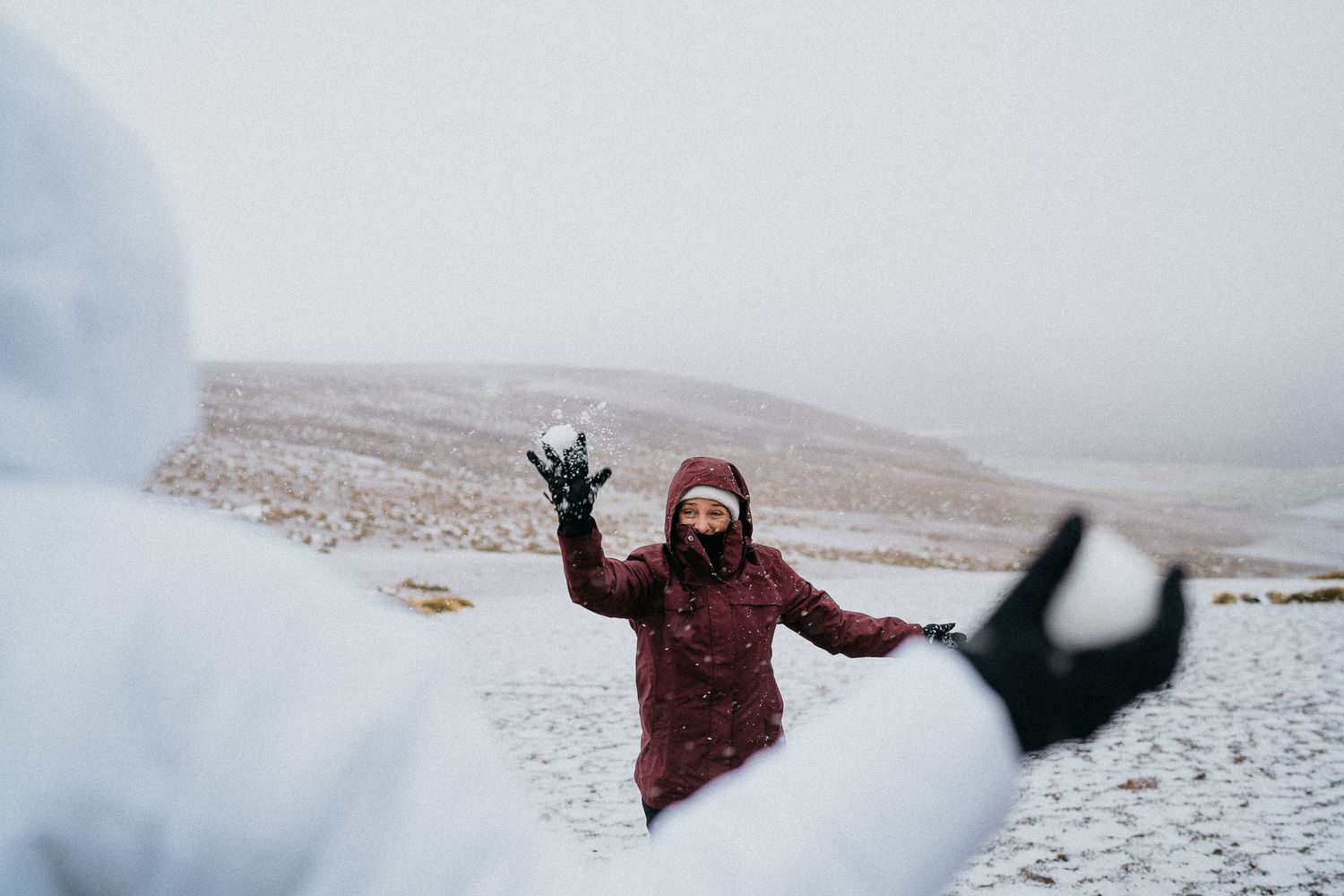 People playing and jumping in snowy weather on desert terrain.