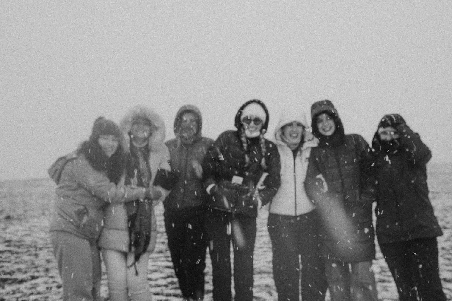 Group photo in black and white during snowfall in desert landscape.