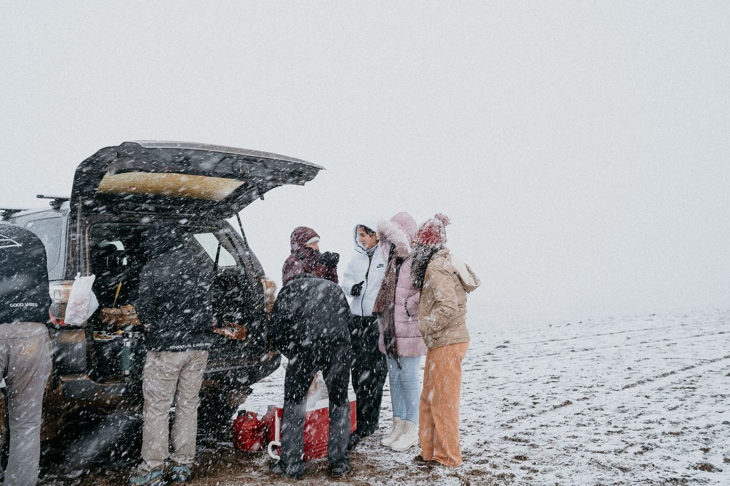 People gathered around vehicles in snowy desert conditions.