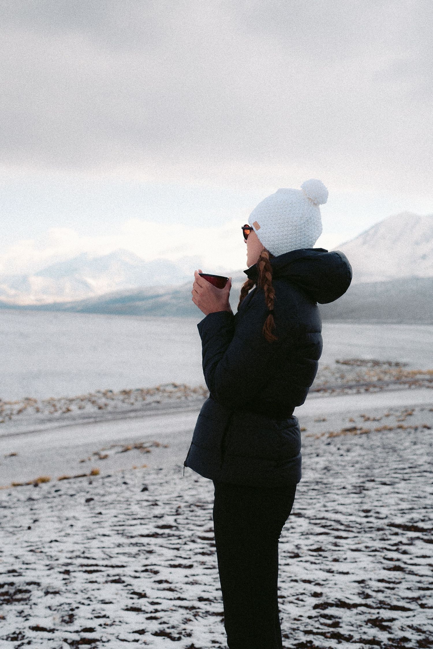 Photographer taking pictures in a snowy mountain landscape with dramatic cloudy skies.