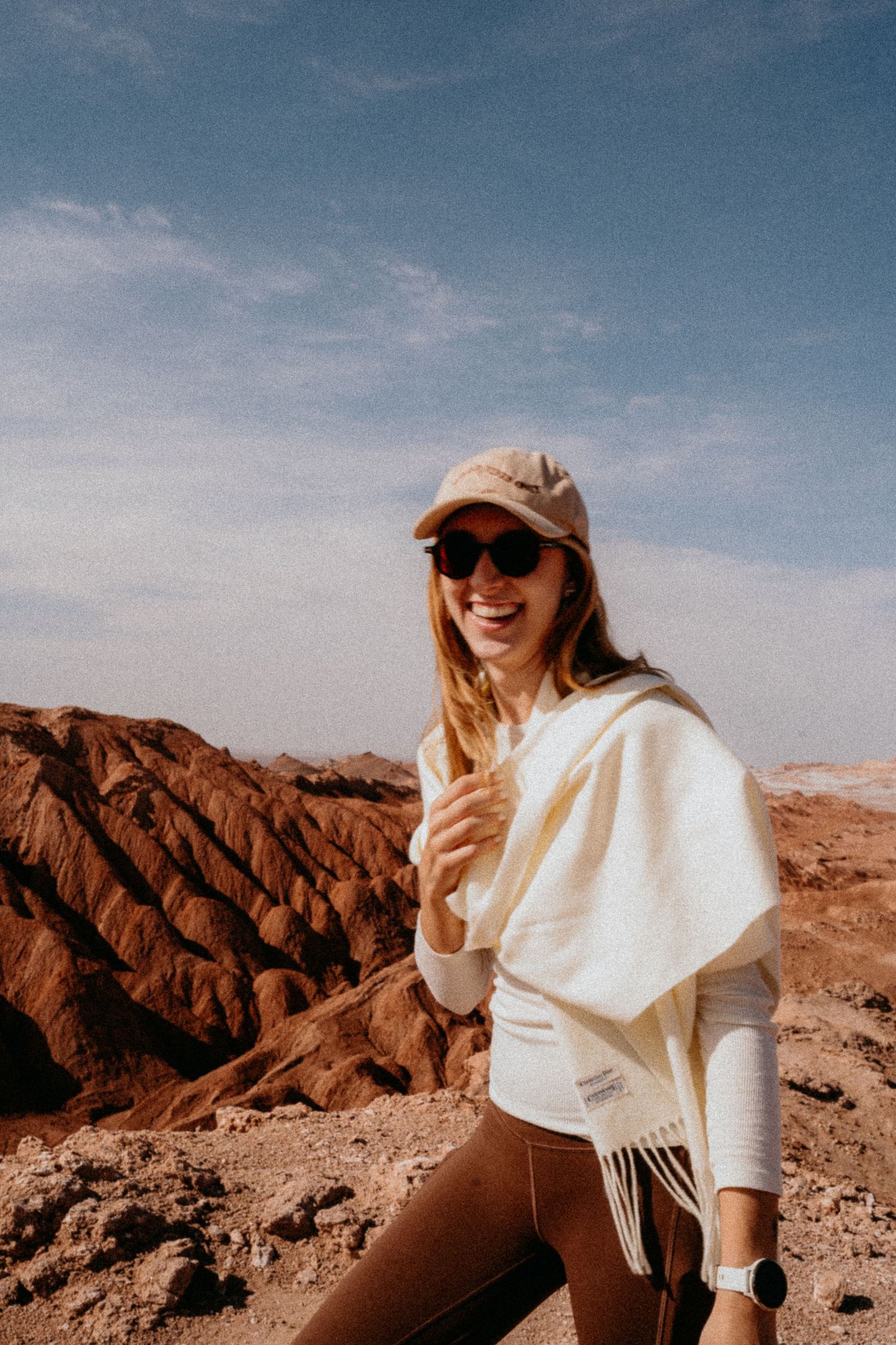 Adventure traveler in white sweater and cap exploring rocky desert terrain.