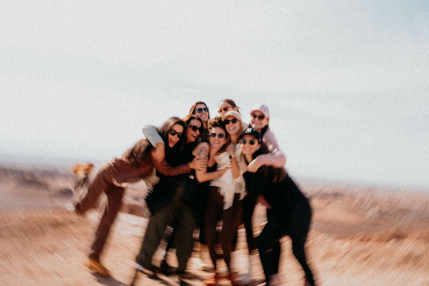 Group photo of friends posing together in desert landscape.