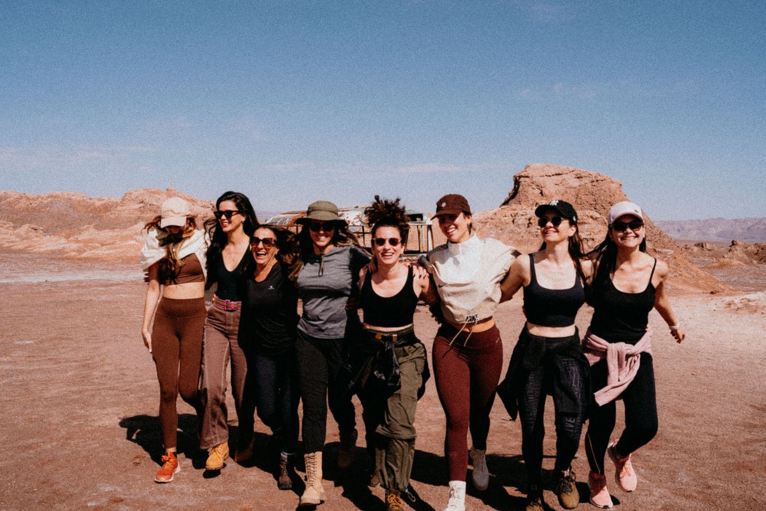 Large group striking fun poses together in desert environment.