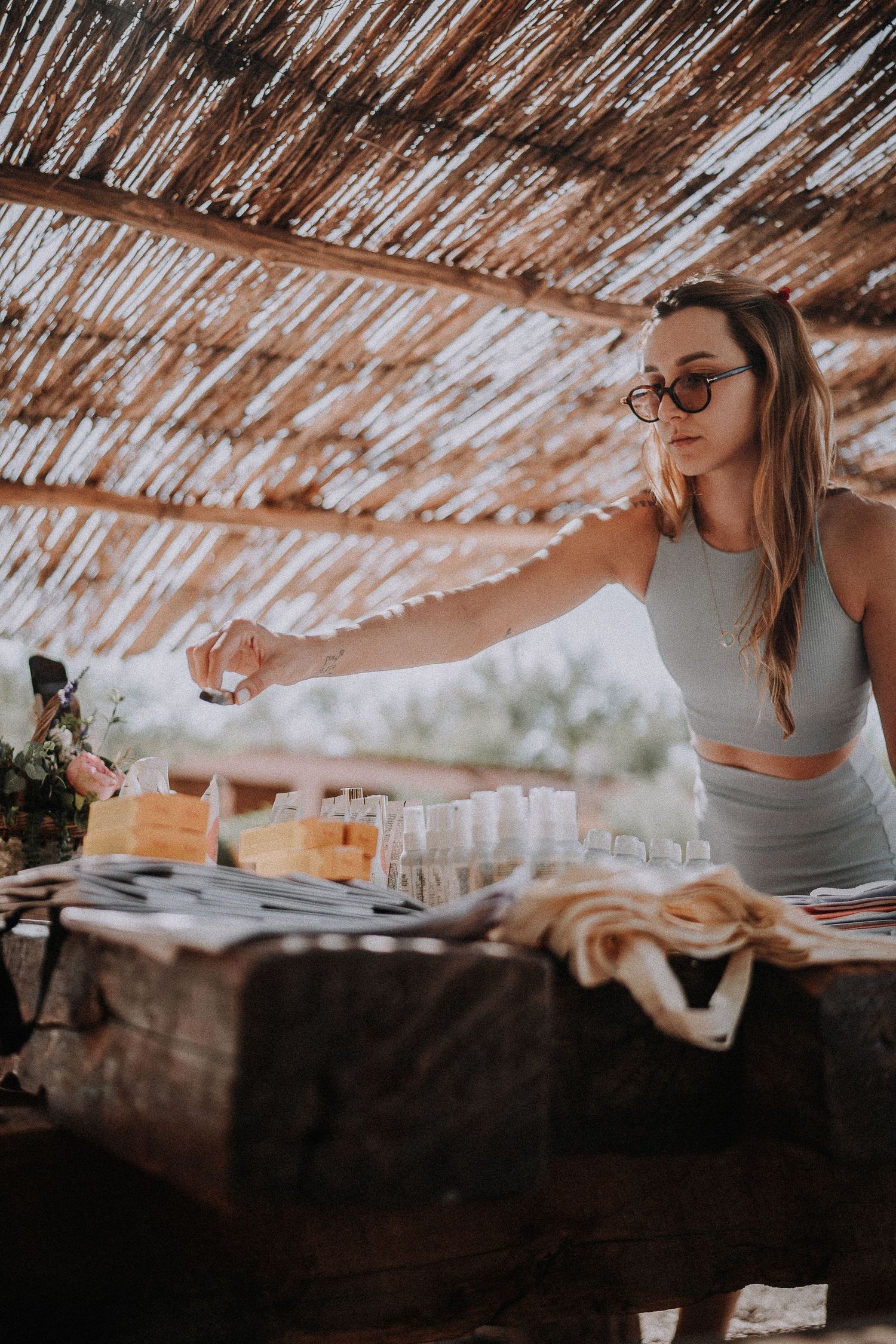 A casual outdoor dining setup under a rustic bamboo pergola with wine glasses and table settings.