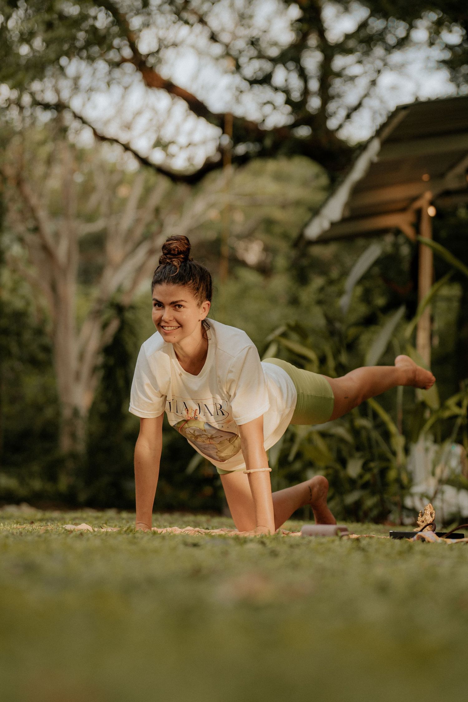 Person in white t-shirt lying playfully on grass in outdoor natural setting.