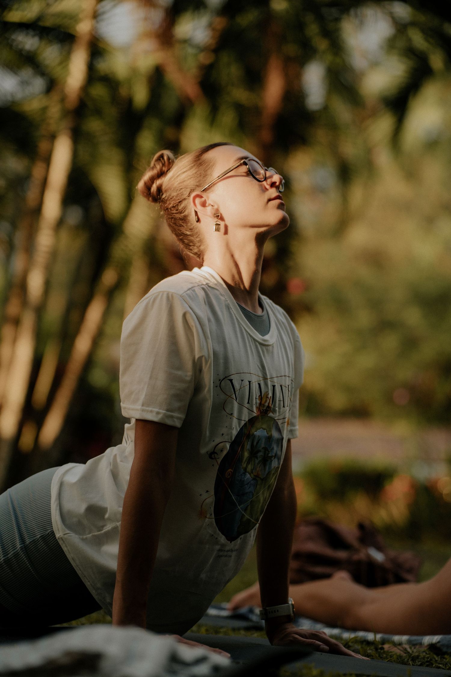 Person relaxing on ground at sunset with trees in background.
