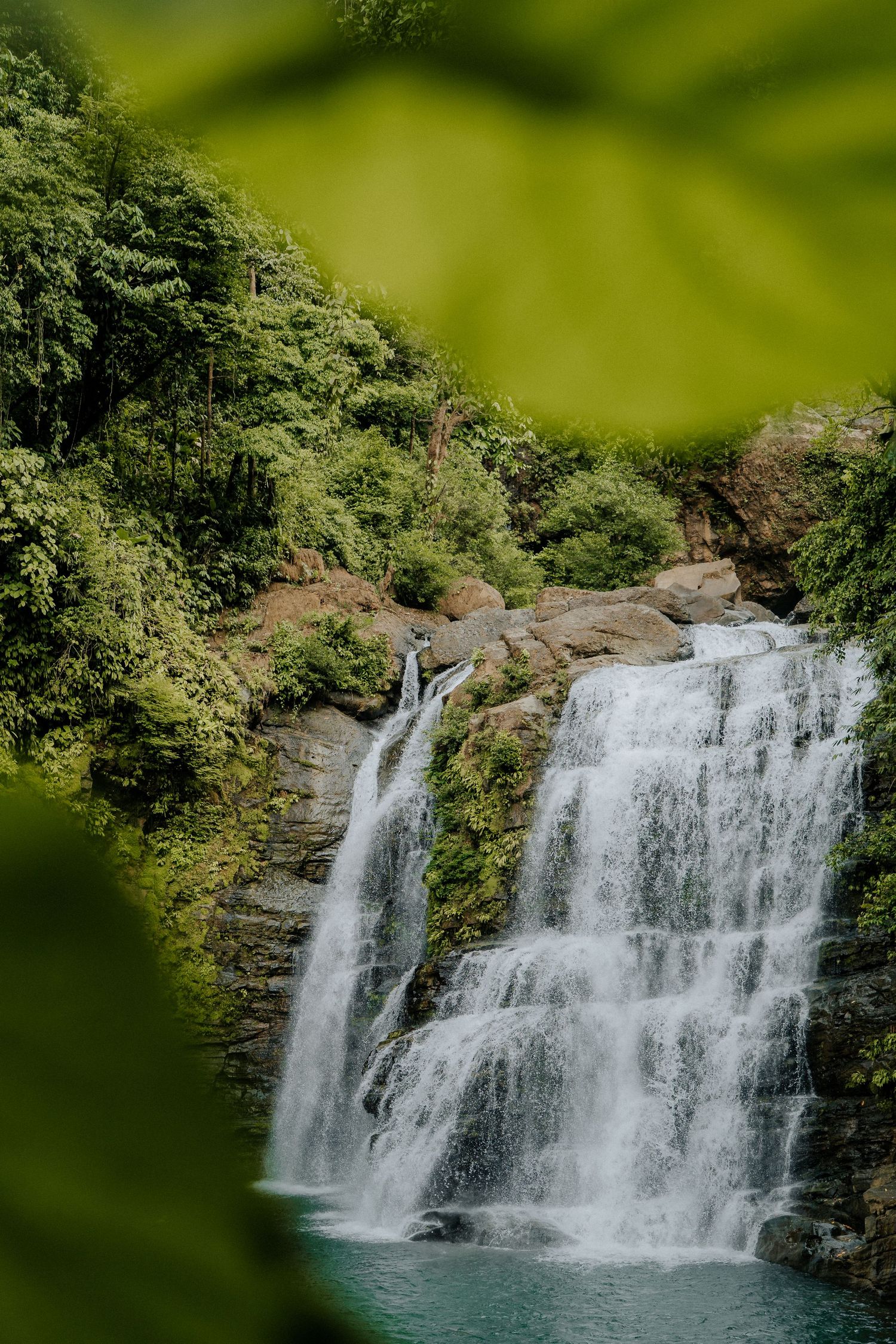 Scenic waterfall cascading down rocky cliff surrounded by lush green forest.